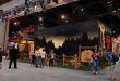 Attendees at New York Comic Con walk past a large Peacock Camp Crystal Lake booth featuring a dark forest mural and a wooden sign.