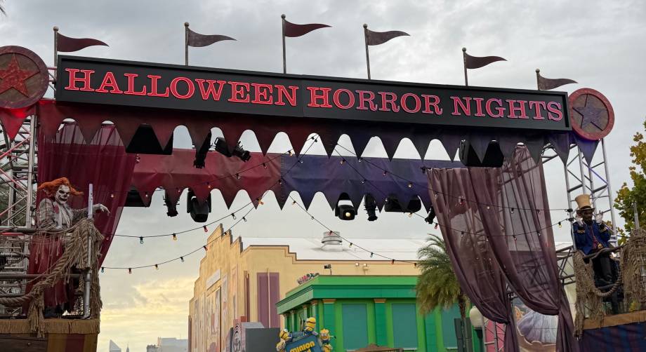 The Universal Orlando Halloween Horror Nights 35 entrance gate features a marquee with the event name, flanked by costumed performers on raised platforms.